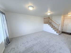 Unfurnished living room featuring light colored carpet and a textured ceiling