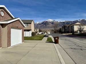 View of asphalt street with a residential view, sidewalks, a mountain view, and curbs