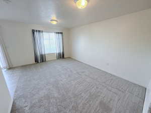 Spare room featuring light carpet and a textured ceiling