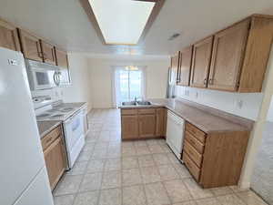 Kitchen featuring a peninsula, white appliances, light countertops, a textured ceiling, and hanging lights