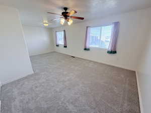 Spare room featuring carpet flooring, a ceiling fan, and a textured ceiling