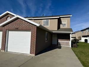 Traditional-style house featuring a garage, a shingled roof, brick siding, and driveway