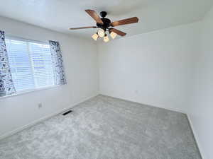 Carpeted empty room featuring a ceiling fan and a textured ceiling