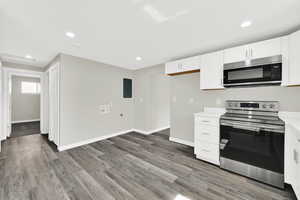 Kitchen with stainless steel appliances, white cabinetry, light wood-style flooring, and recessed lighting