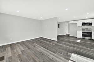 Unfurnished living room featuring recessed lighting and dark wood-type flooring