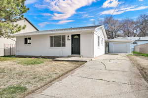 Single story home with concrete driveway, brick siding, crawl space, a shingled roof, and an outdoor structure