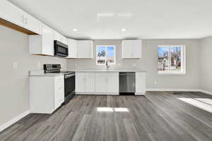 Kitchen with light countertops, stainless steel appliances, white cabinetry, light wood-style floors, and recessed lighting