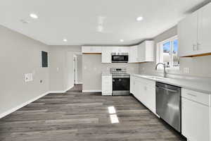 Kitchen with stainless steel appliances, white cabinetry, dark wood-style floors, recessed lighting, and electric panel