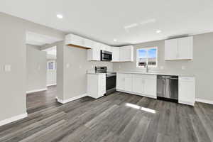 Kitchen with white cabinetry, stainless steel appliances, light countertops, dark wood finished floors, and recessed lighting