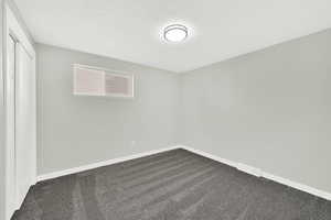 Unfurnished bedroom with dark carpet, a closet, and a textured ceiling
