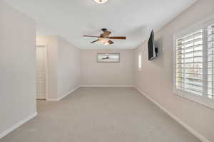 Unfurnished room featuring light colored carpet and a ceiling fan