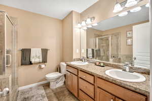 Full bath featuring double vanity, a shower stall, and light tile patterned floors