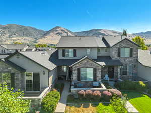View of front facade with stone siding, a mountain view, stucco siding, and a shingled roof