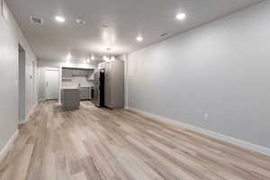 Kitchen featuring gray cabinetry, open floor plan, a chandelier, light countertops, and light wood finished floors