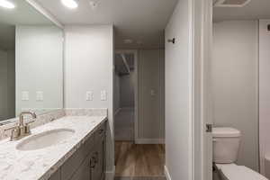 Full bathroom with vanity, dark wood-style floors, and a textured ceiling
