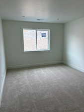 Spare room featuring light colored carpet and a textured ceiling