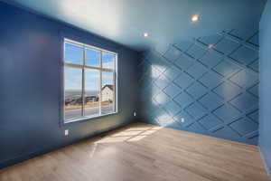 Unfurnished room featuring wood finished floors, a decorative wall, a textured ceiling, and recessed lighting