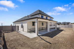 Rear view of house featuring a patio area, stucco siding, a fenced backyard, and roof with shingles