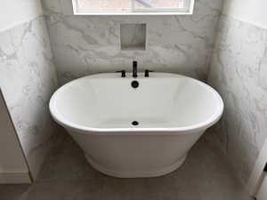 Full bath featuring tile walls and a freestanding tub