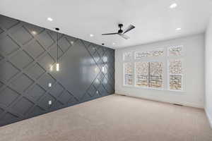 Carpeted empty room featuring a decorative wall, an accent wall, a ceiling fan, and recessed lighting