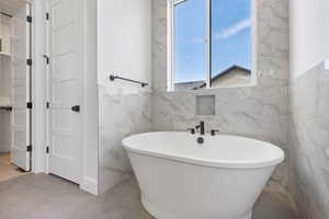 Full bath with a soaking tub and tile walls