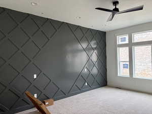 Unfurnished room with a decorative wall, an accent wall, carpet floors, and ceiling fan