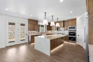 Kitchen with backsplash, a kitchen island, stainless steel appliances, light stone counters, and pendant lighting