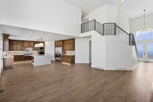 Unfurnished living room featuring a chandelier, dark wood-style flooring, french doors, and a high ceiling