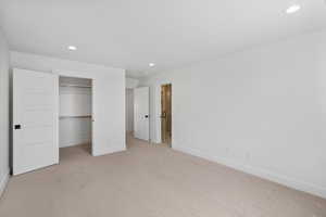 Unfurnished bedroom with recessed lighting, light carpet, and a walk in closet