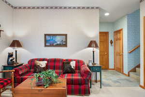 Carpeted living area featuring wallpapered walls and recessed lighting