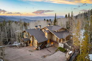 View of front of property featuring a shingled roof, a chimney, a mountain view, concrete driveway, and an attached garage