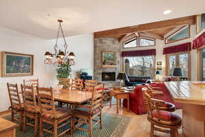 Dining space featuring light wood finished floors, a fireplace, lofted ceiling, and hanging lights