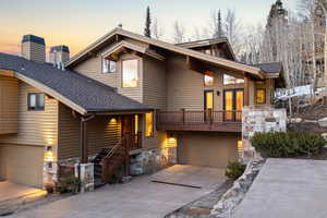 View of front facade with a garage, roof with shingles, concrete driveway, log veneer siding, and a chimney