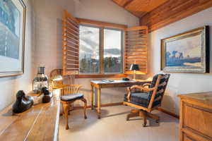 Office area with wallpapered walls, light colored carpet, and lofted ceiling