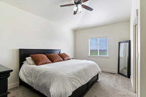 Bedroom with light colored carpet, vaulted ceiling, and ceiling fan