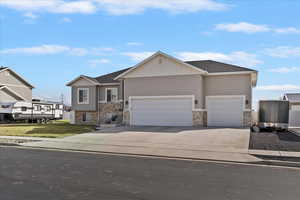 View of front of house with stone siding, an attached garage, driveway, and stucco siding