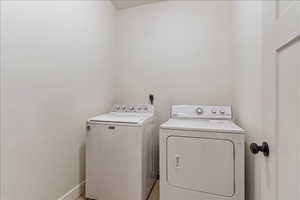 Laundry room with washer and clothes dryer and baseboards
