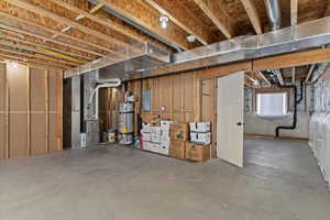 Below grade area with heating unit, strapped water heater, and electric panel