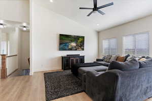 Living area with lofted ceiling, ceiling fan, light wood-style flooring, a fireplace, and recessed lighting