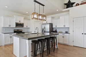Kitchen featuring white cabinetry, a breakfast bar, stainless steel appliances, and light wood-style flooring