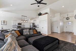 Living room featuring light wood-style floors, ceiling fan, recessed lighting, and vaulted ceiling