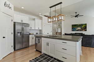 Kitchen featuring stainless steel appliances, dark countertops, white cabinetry, and open floor plan