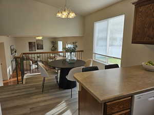 Dining area with light wood finished floors, suspended lighting, and lofted ceiling