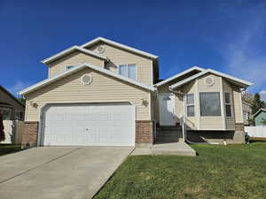 Traditional-style home featuring concrete driveway, an attached garage, entry steps, and brick siding