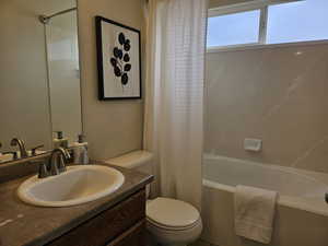 Full bathroom with vanity, shower / bath combo, and a textured wall