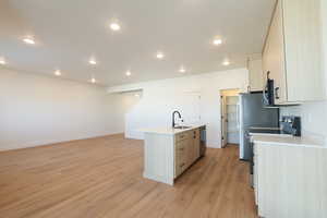 Kitchen with stainless steel appliances, light wood finish cabinetry, a kitchen island with sink, light wood-style flooring, and recessed lighting