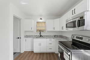 Kitchen featuring stainless steel appliances, dark wood finished floors, and white cabinets