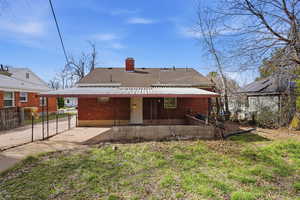 Back of house with a chimney, a shingled roof, a gate, a patio area, and brick siding