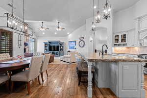 Kitchen featuring hanging lights, glass insert cabinets, ceiling fan, a kitchen breakfast bar, and dark stone countertops