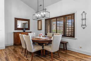 Dining space with hardwood / wood-style floors, suspended lighting, and vaulted ceiling